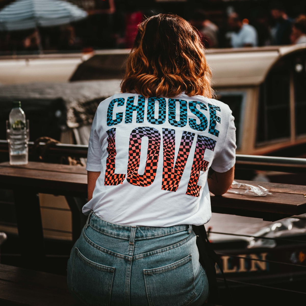 A woman facing away from the camera, wearing a shirt that says "choose love" 